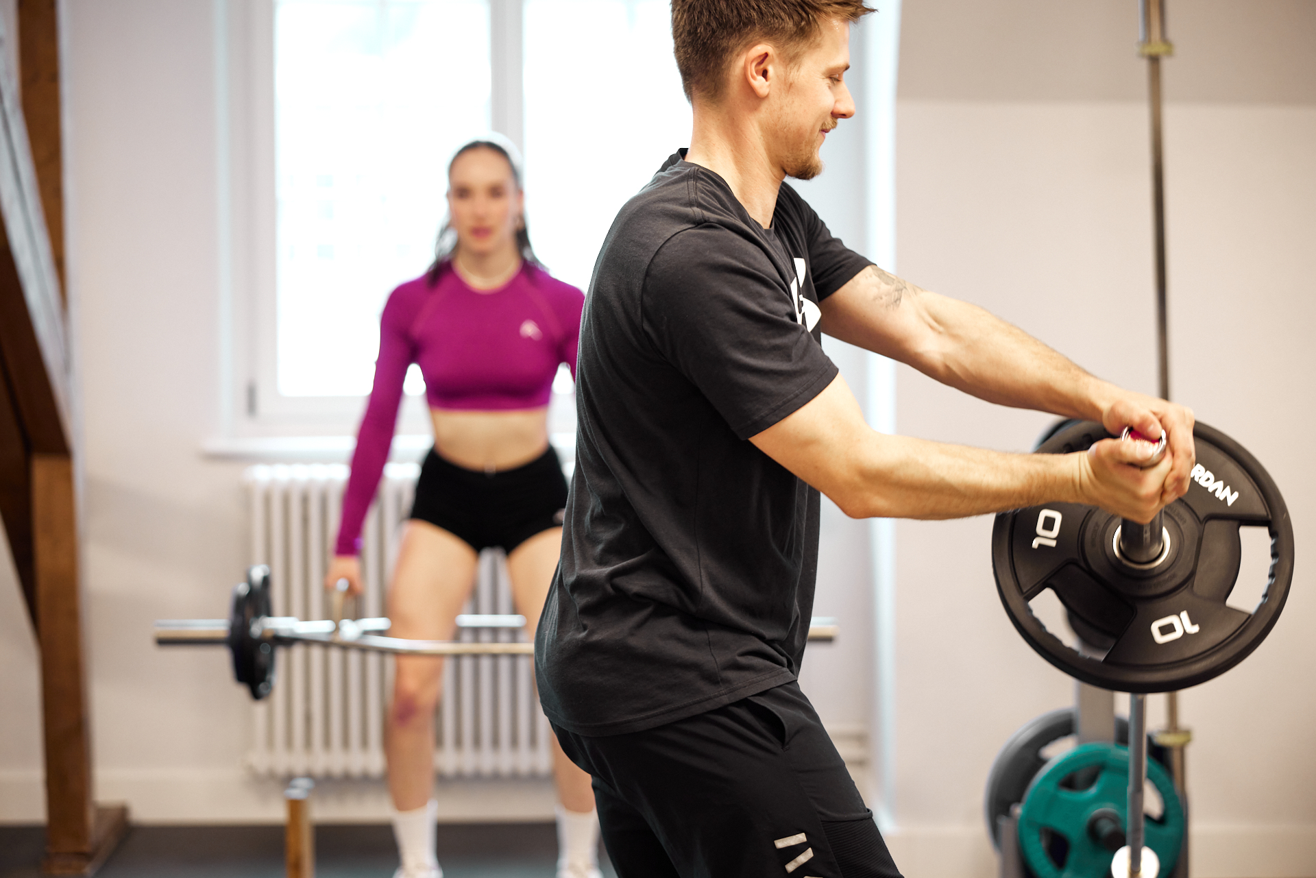 Athletin trainiert mit Langhantel unter Anleitung